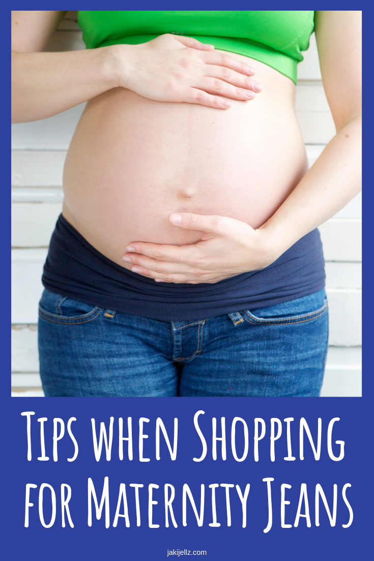 Young pregnant woman in jeans holding stomach