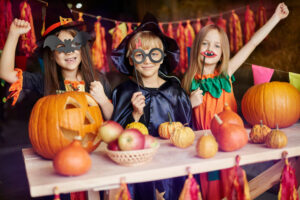 Kids wearing costumes and holding Jack-o'-lanterns ready to trick-or-treat at halloween.